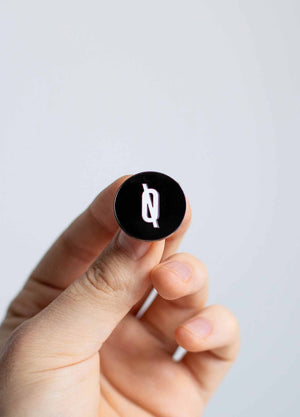 Hand holding O Logo enamel pin