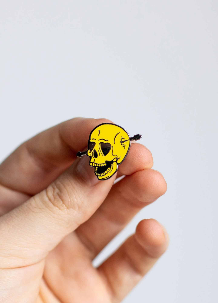 Hand holding Skull enamel pin
